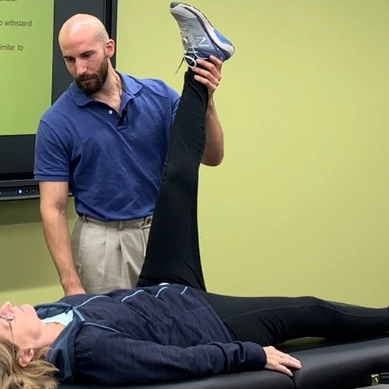 A man and a woman engage in a physical therapy session, working on exercises to improve mobility and strength